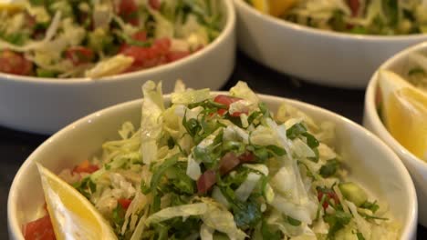 fresh vegetable salad served in bowls with lemon slices on the side, close up shot
