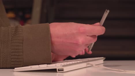 nervous hand spins pen in fingers while other writes on computer keyboard