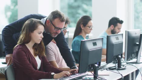 teacher helps students in computer class during lecture.