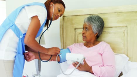 Doctora-Midiendo-La-Presión-Arterial-De-Una-Mujer-Mayor-En-El-Dormitorio-4k