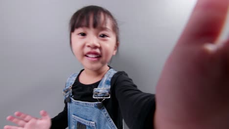 happy little asian girl using smartphone for video call, waving hand and speaking and talking witn smile, greeting teacher and classmates