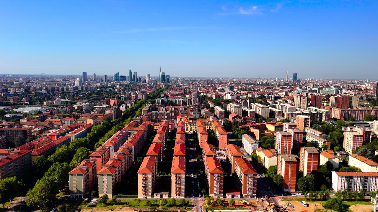Bright and sunny day showcases an extensive cityscape filled with modern buildings, green parks, and a clear blue sky. The vibrant area highlights urban life and nature's beauty