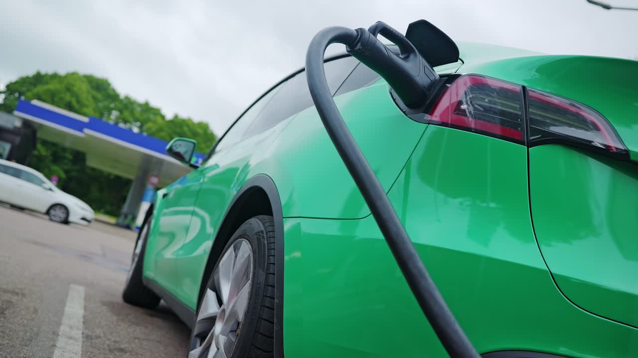 Artistic low tilt up shot of charging electric vehicle in city, overcast sky