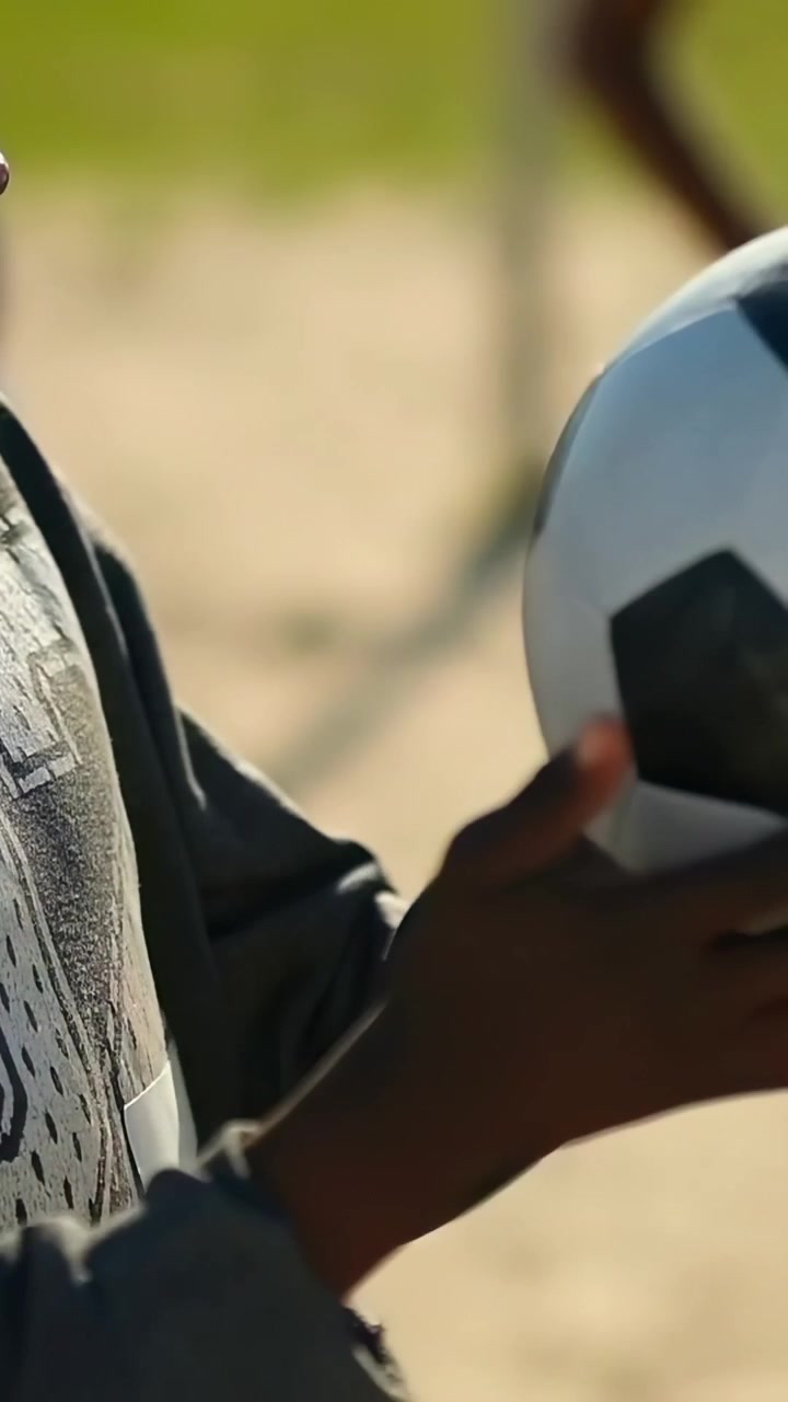 Video verticale: Bambino con felpa con cappuccio numero 9 che riceve un passaggio, tiene la palla con le mani al parco, mantenendo il controllo.