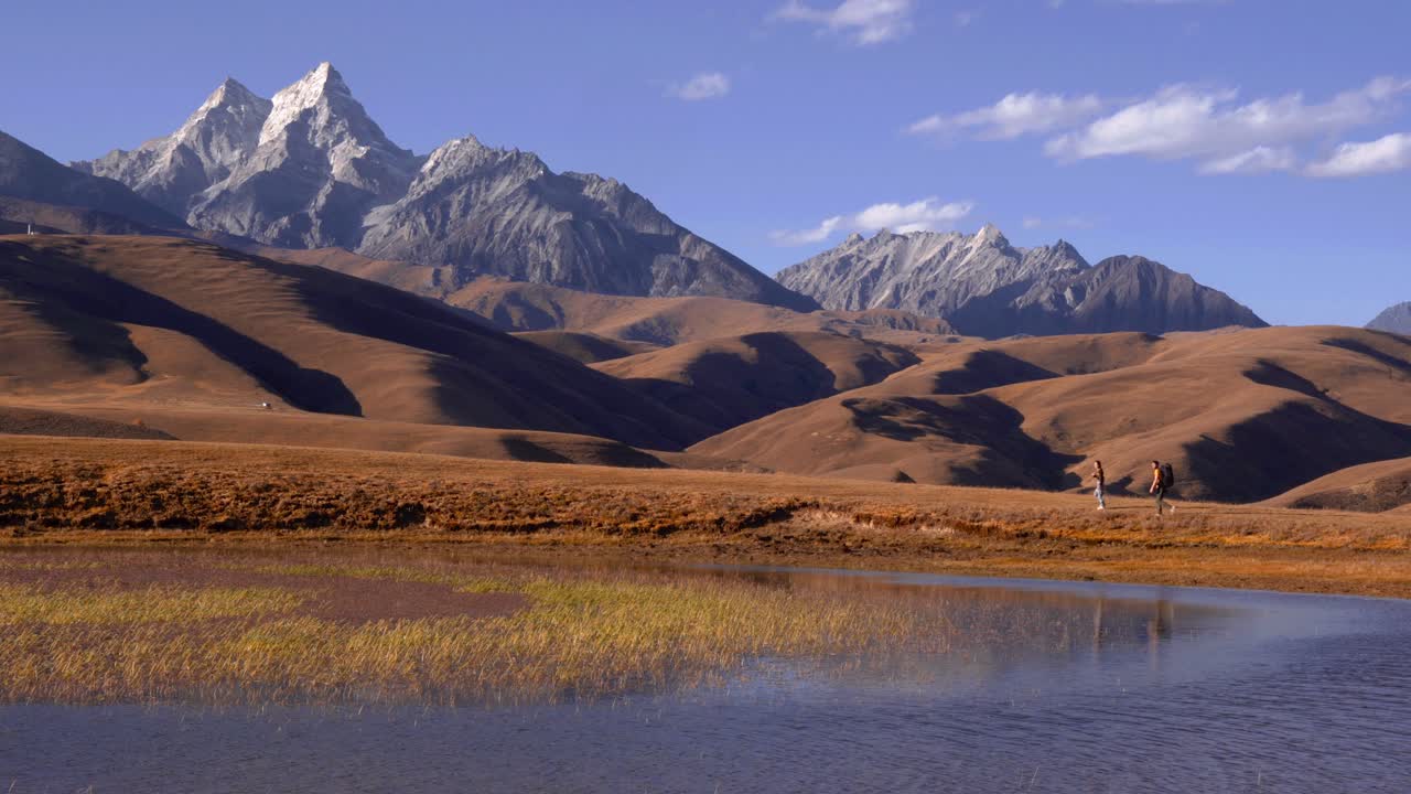Una coppia esplora camminando lungo le rive del lago nelle montagne del Sichuan con cime mozzafiato