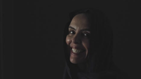 a muslim woman looks up out of the darkness with a big smile