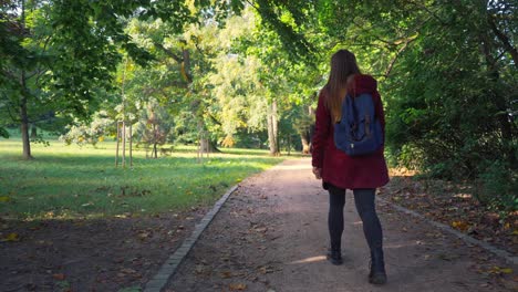 woman with a backpack and long beautiful hair is walking along a path in the forest