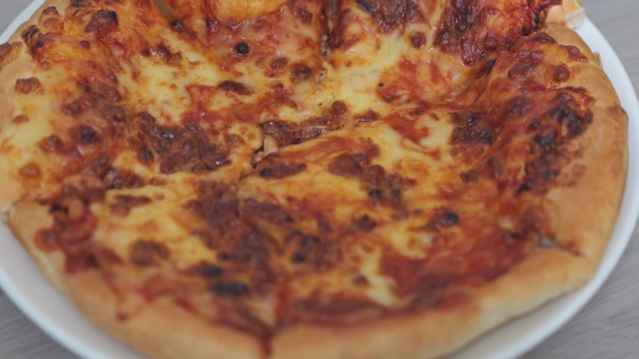 Primo piano di pizza al formaggio appena sfornata con formaggio fuso dorato e bollente, crosta croccante e una consistenza calda e invitante