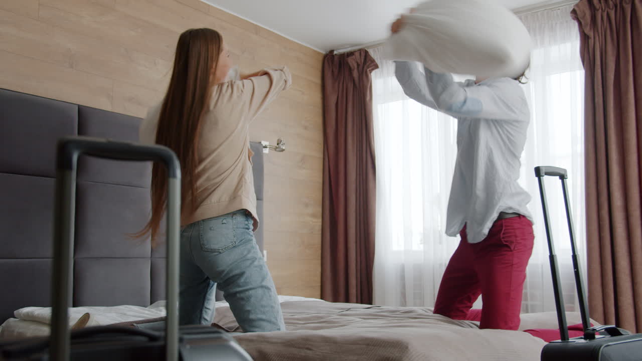 Happy Couple Having Pillow Fight in Hotel Room