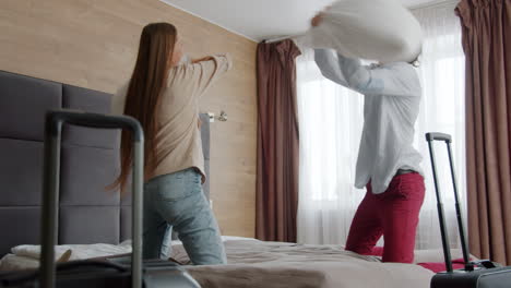 happy couple having pillow fight in hotel room