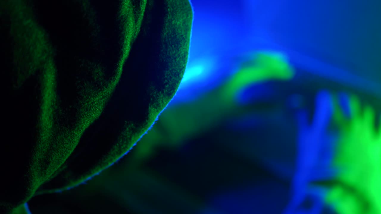 Person in dark clothing under neon light