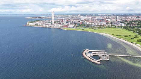 malmo seaside and cityscape with beach and wharf, turning torso and commercial area on background - aerial