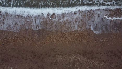 Una-Toma-Lenta-Y-Creciente-De-Un-Dron-De-4k-De-Olas-Que-Llegan-A-Una-Playa-De-Guijarros-En-El-Sur-De-Devon