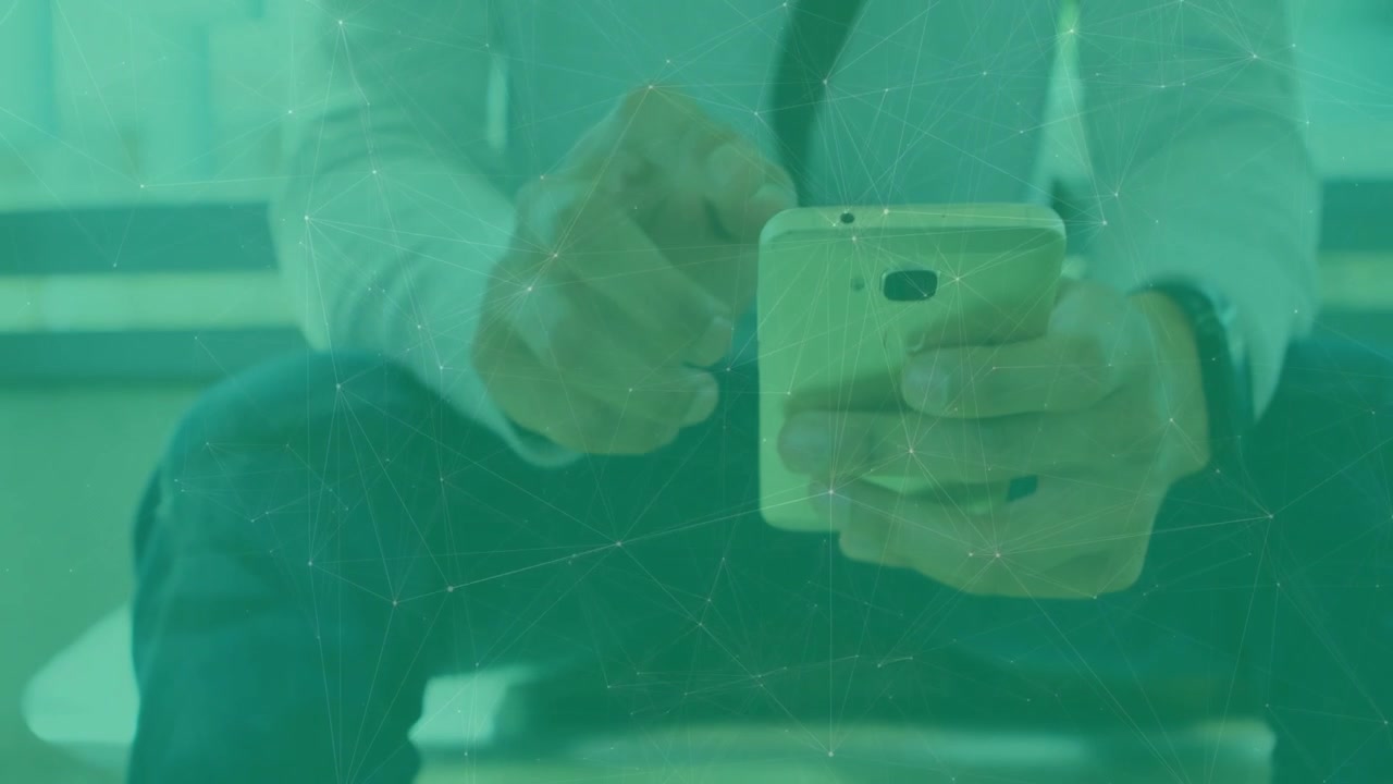 Uomo seduto nella lobby aziendale, inizia a usare il telefono mentre controlla i messaggi sotto un vetro verde.