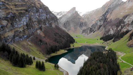 sobrevuelo aéreo lejos de seealpsee en appenzell, suiza con movimiento panorámico hacia abajo desde los picos alpstein hacia el reflejo en el lago