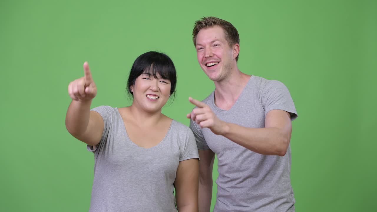 Young multi-ethnic couple smiling and waving hands together