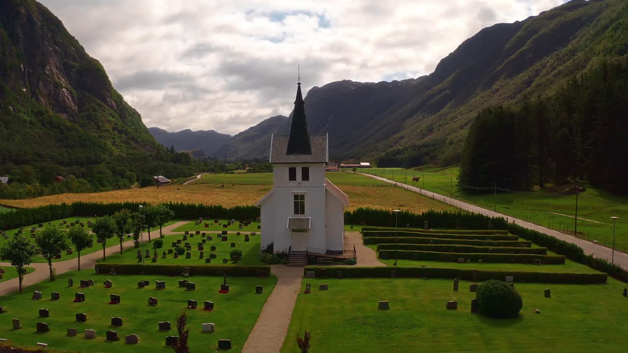 Scenic aerial shot of a church beside a cemetery surrounded by lush mountains in Norway
