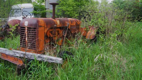 an old tractor oven taken by the trees and shrubs in a field