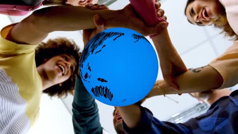 Animation-of-blue-globe-rotating-over-happy-diverse-colleagues-linking-hands-at-casual-office