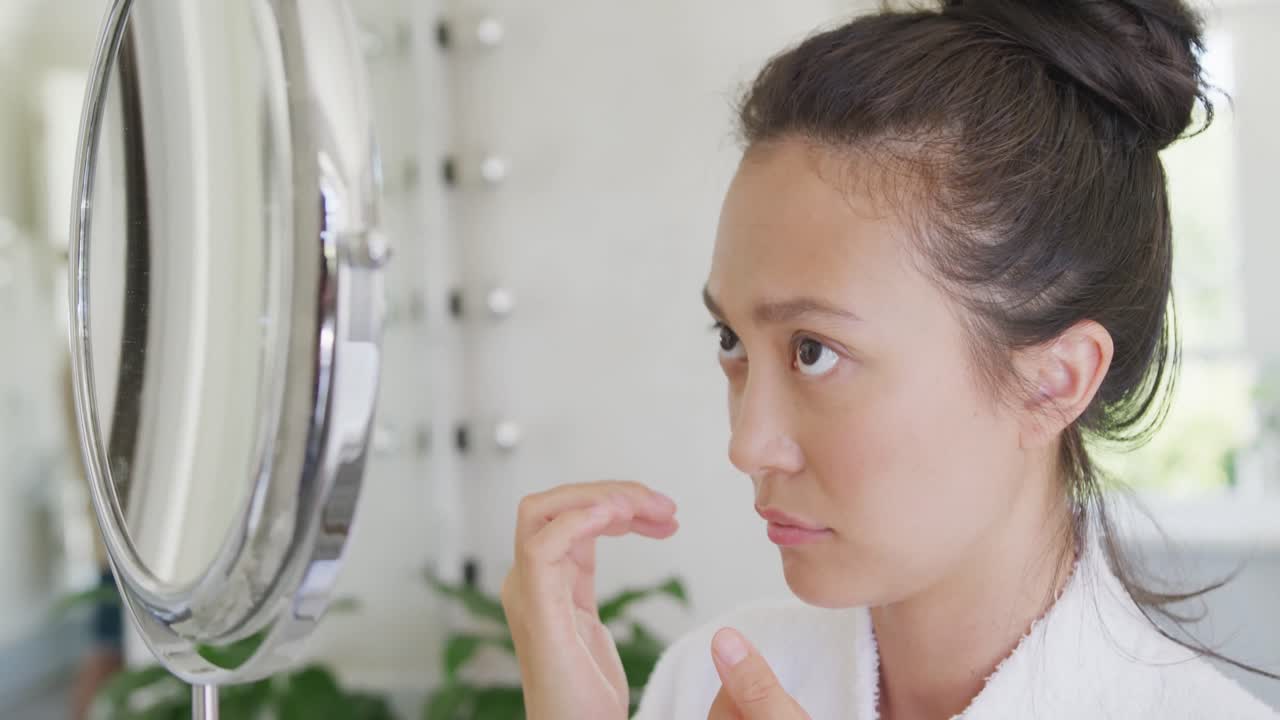 슬로우 모션으로 화장실에서 거울을 보고 얼굴을 만지는 행복한 아시아 여성