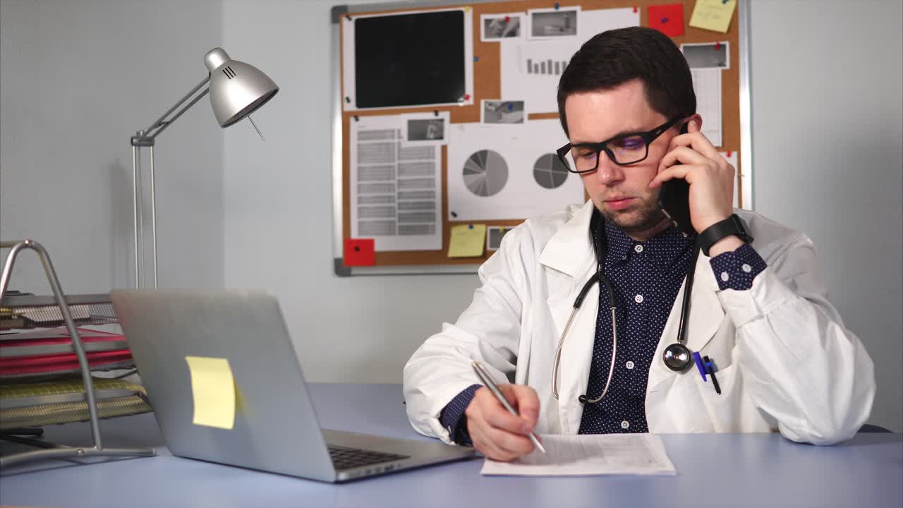 el médico hablando por teléfono y escribiendo notas