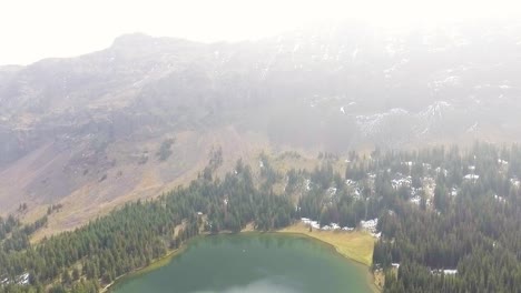 Drone-pulls-back-revealing-more-of-the-lake-and-large-mountains-surrounding-the-area