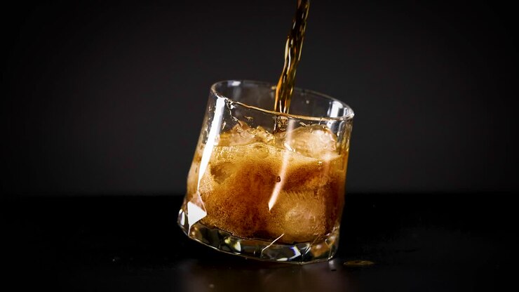 Cola being poured into a glass with ice