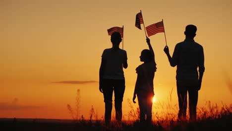 Familia-Con-Niño-Ondeando-Banderas-Al-Atardecer-Vista-Trasera