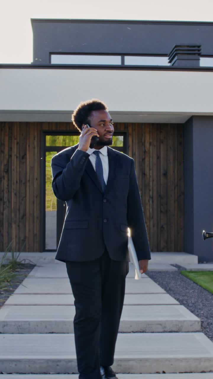 Businessman Talking on Phone While Walking Up to Modern Home