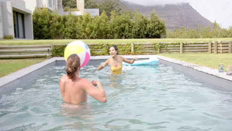 una joven pareja biracial disfruta de un momento lúdico en una piscina
