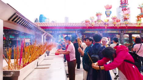 people praying with incense sticks in hong kong