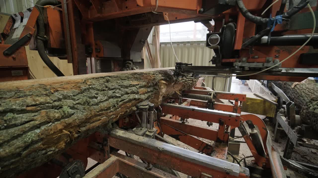 Industriell sagbruksmaskin kutter en stor tømmerstokk