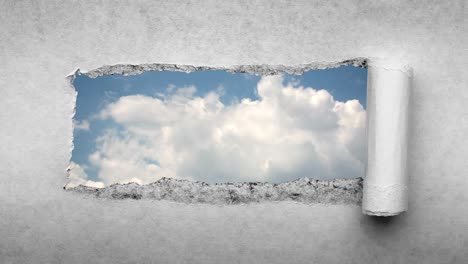 un video creativo de 4k de nubes que se mueven rápidamente en el cielo azul que son visibles a través de un agujero con bordes rasgados en viejo papel vintage retro grunge.