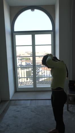woman doing yoga exercises in a room with a city view