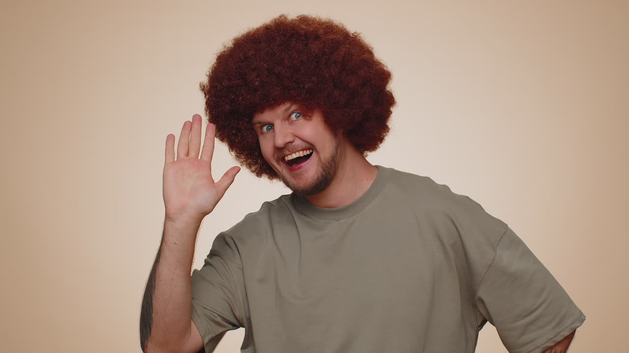 Bearded man smiling friendly at camera and waving hands gesturing hello or goodbye, welcoming