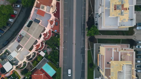 drone view town street with asphalt road running between residential buildings.