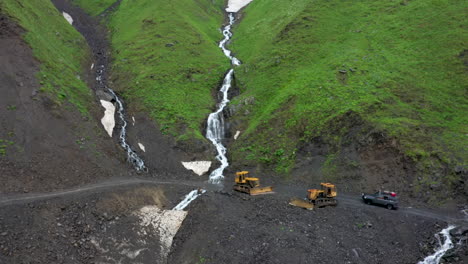 Drone-shot-of-vehicle-passing-construction-equipment-on-the-Road-to-Tusheti,-one-of-the-worlds-most-dangerous-roads