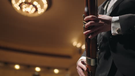 adult-man-in-concert-suit-is-playing-bassoon-on-scene-of-old-opera-theater-musician-and-symphony