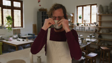 portrait of male caucasian potter wearing face mask at pottery studio