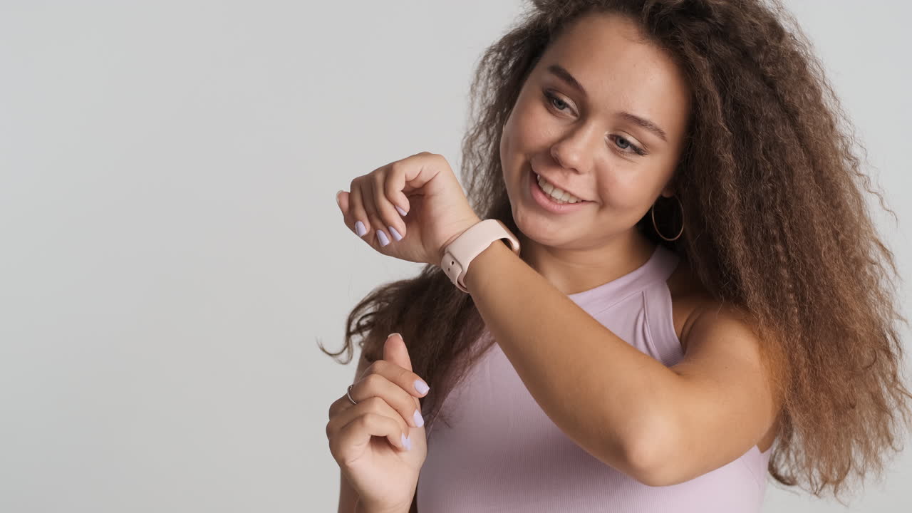 una mujer caucásica de cabello rizado haciendo una llamada en un reloj inteligente.