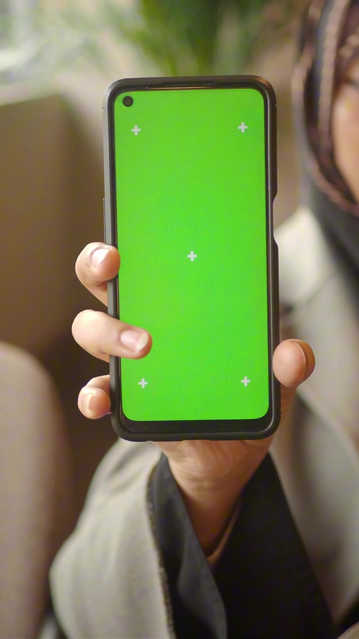 Persona che tiene in mano uno smartphone verticale con schermo verde
