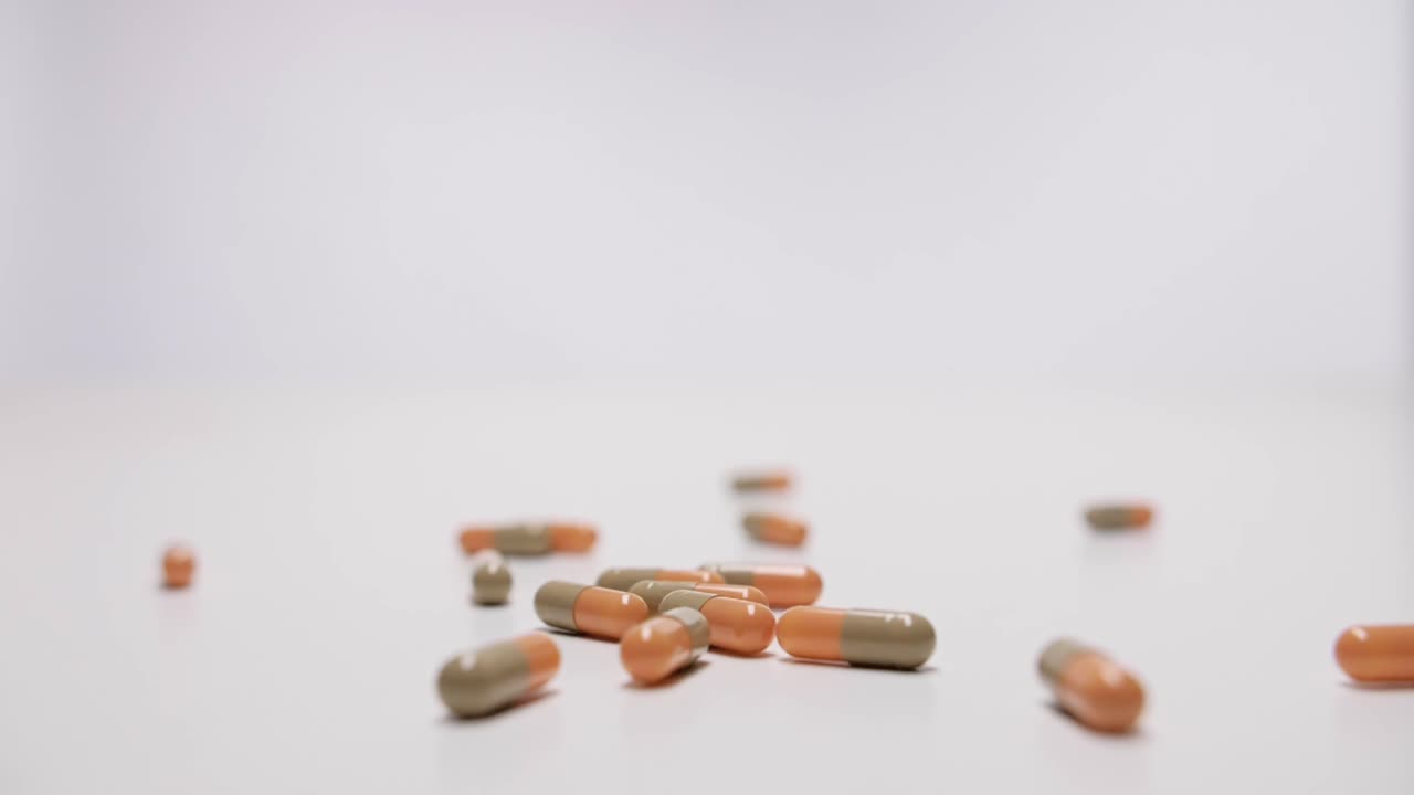 Medicine capsules falling on white background in slow motion.