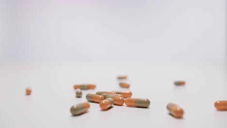 medicine capsules falling on white background in slow motion.