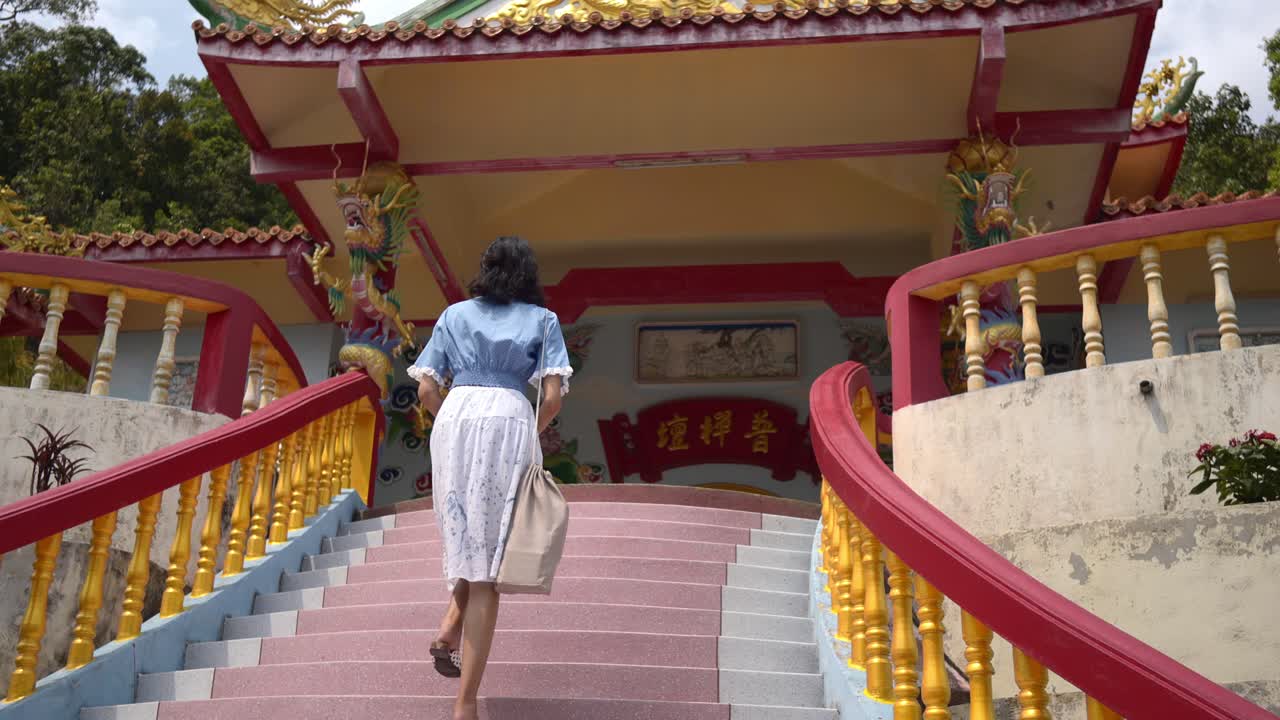 화려한 계단을 따라 중국 사원으로 걸어가는 여성의 모습을 가까이에서