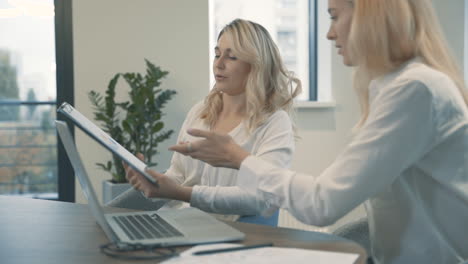 beautiful young blonde business women discuss documents and good results in the company