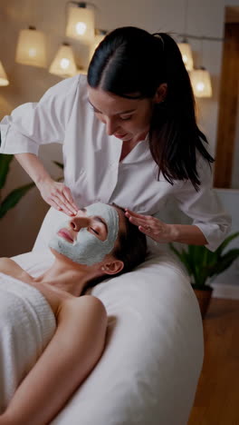 Woman receiving a face mask application at a spa