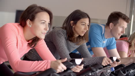 side view of a spinning class on exercise bikes at a gym, close up