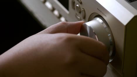 men's hands adjusting volume control of the amplifier form the home theater system with the adjust button for broadcasting and music