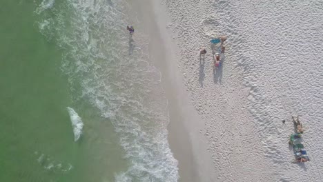 mar turquesa con olas espumosas en una playa de arena - antena arriba hacia abajo