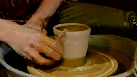 professional potter shaping mug with special tool in pottery workshop